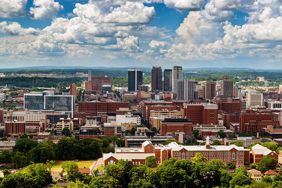 Birmingham, AL Insurance - Sweeping View of Birmingham, Alabama City Skyline and Surrounding Trees, White Puffy Clouds Overhead in a Blue Sky